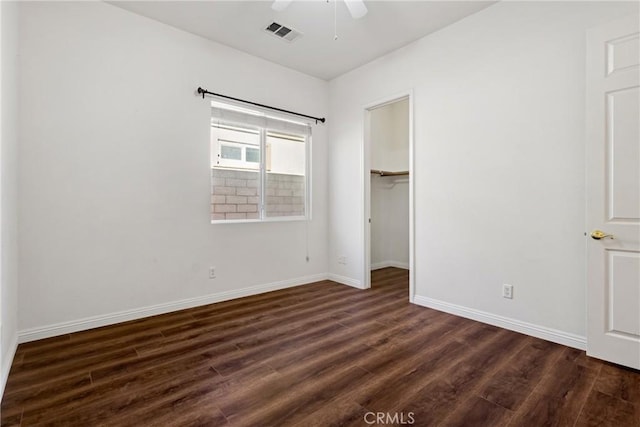 unfurnished bedroom with ceiling fan, dark hardwood / wood-style floors, a spacious closet, and a closet