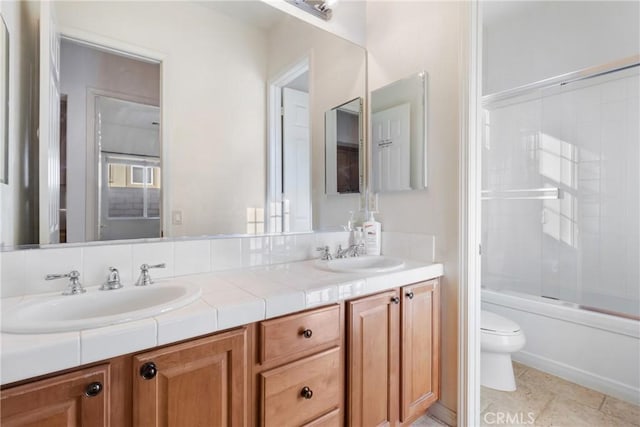 full bathroom with tile patterned floors, bath / shower combo with glass door, toilet, and vanity