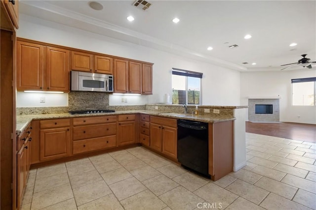 kitchen featuring kitchen peninsula, ceiling fan, light stone countertops, black appliances, and sink