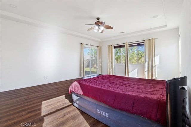 bedroom featuring ceiling fan, wood-type flooring, and a raised ceiling