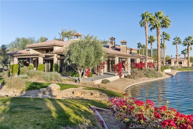 rear view of property featuring a water view and a lawn