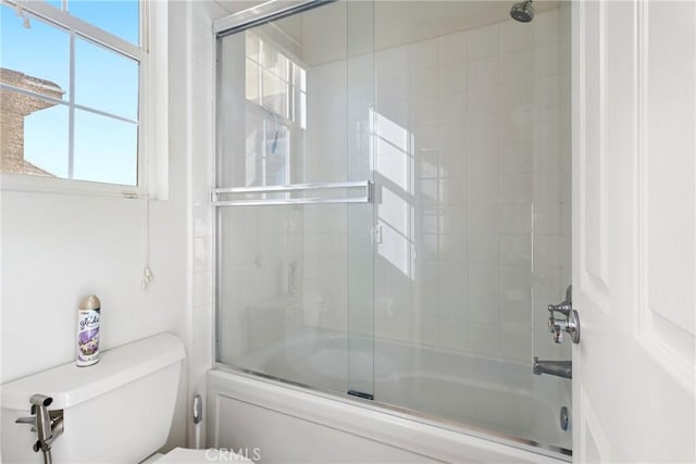 bathroom featuring toilet and combined bath / shower with glass door