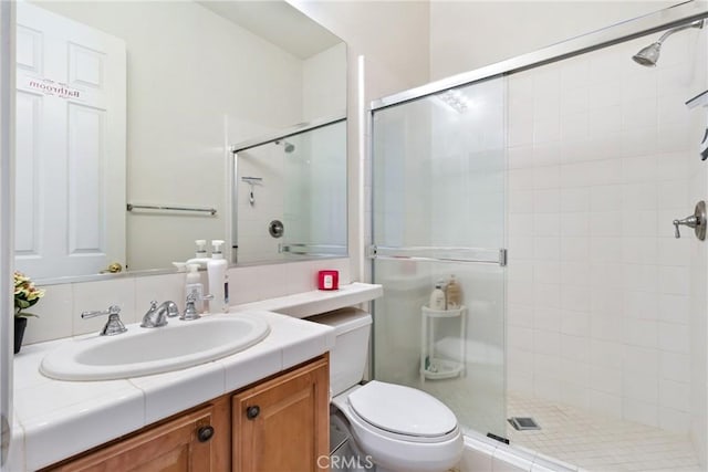 bathroom featuring toilet, a shower with door, and vanity