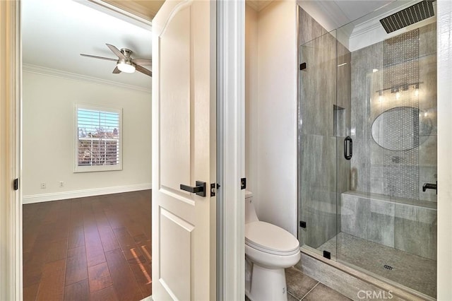 bathroom featuring toilet, ceiling fan, hardwood / wood-style floors, crown molding, and a shower with door