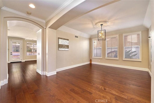 empty room with dark hardwood / wood-style floors, crown molding, a chandelier, and a healthy amount of sunlight