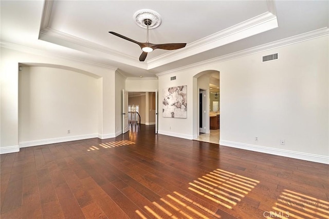 empty room featuring ceiling fan, crown molding, dark hardwood / wood-style floors, and a raised ceiling