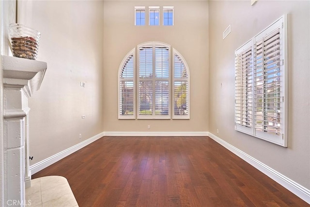 unfurnished room with a high ceiling and dark hardwood / wood-style flooring