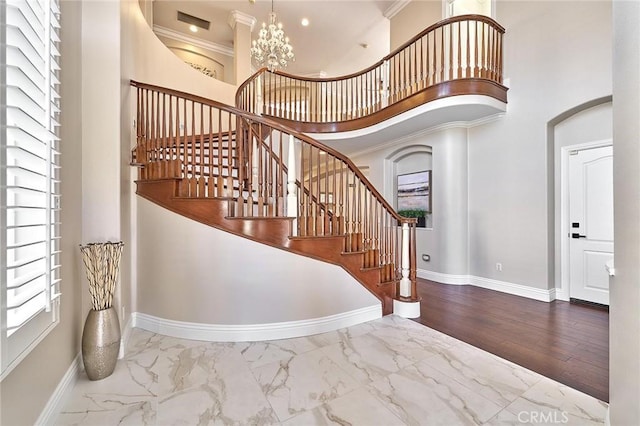 stairs featuring a chandelier, crown molding, and a towering ceiling