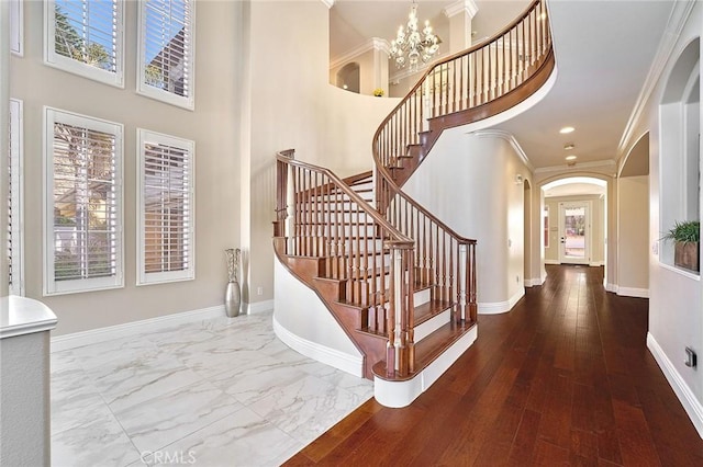 staircase featuring a notable chandelier, crown molding, and a towering ceiling