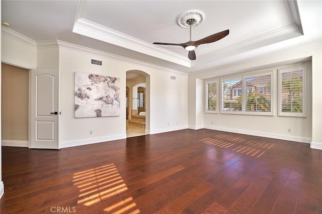 unfurnished room featuring dark wood-type flooring, a tray ceiling, and ornamental molding