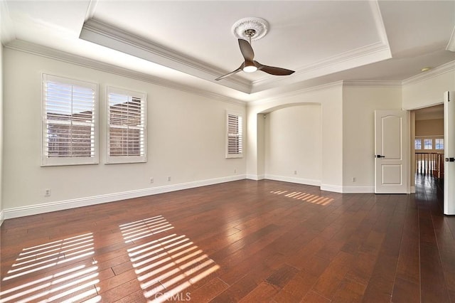 spare room featuring a raised ceiling, ceiling fan, dark wood-type flooring, and ornamental molding