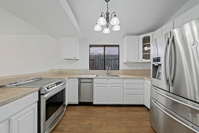 kitchen with stainless steel appliances, a chandelier, white cabinetry, and hanging light fixtures