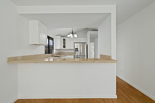 kitchen with kitchen peninsula, stainless steel refrigerator with ice dispenser, and white cabinetry