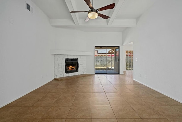 unfurnished living room featuring ceiling fan, light tile patterned floors, a fireplace, and beam ceiling