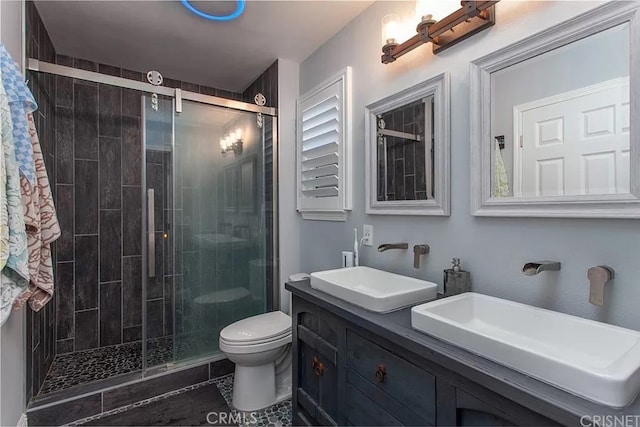 bathroom featuring toilet, tile patterned floors, a shower with shower door, and vanity