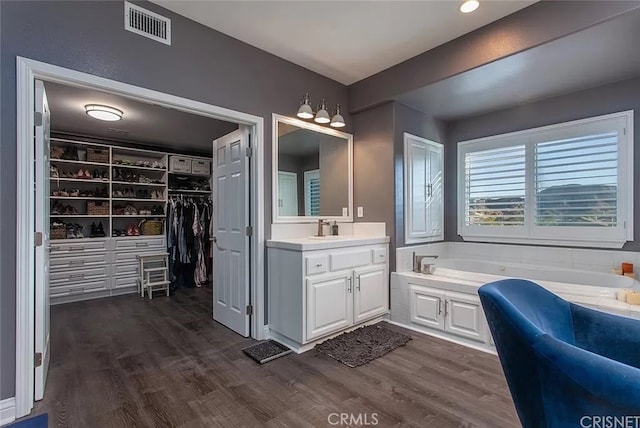 bathroom with a washtub, hardwood / wood-style floors, and vanity