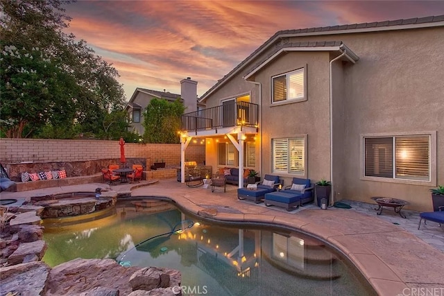 pool at dusk featuring an outdoor living space with a fire pit, an in ground hot tub, and a patio