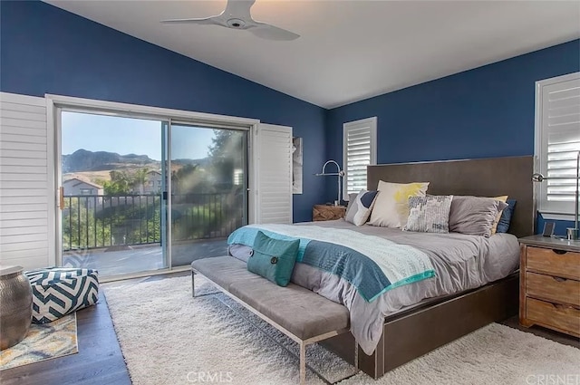 bedroom with access to exterior, hardwood / wood-style flooring, a mountain view, vaulted ceiling, and ceiling fan