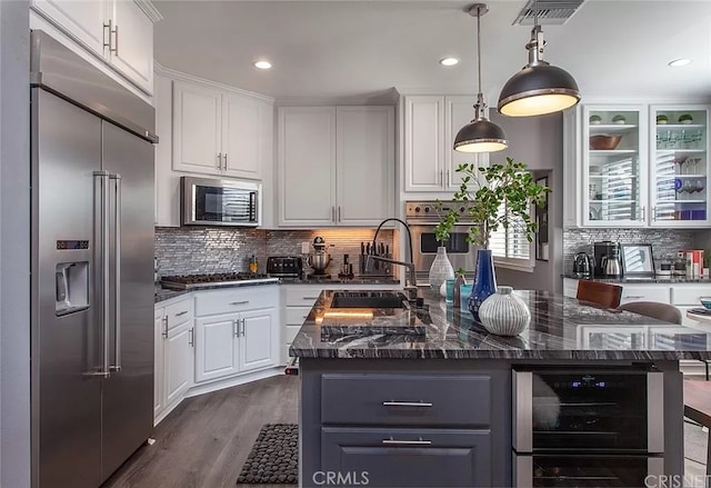 kitchen featuring stainless steel appliances, sink, white cabinets, and a kitchen island with sink