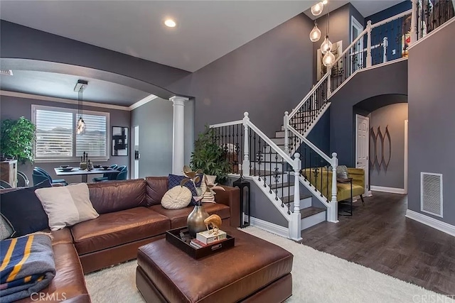 living room with an inviting chandelier, ornamental molding, ornate columns, and wood-type flooring