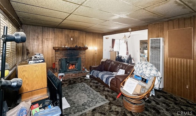 carpeted living room featuring a drop ceiling and wood walls