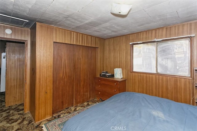 bedroom featuring fridge, a closet, carpet, and wooden walls