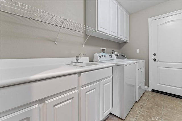 clothes washing area featuring cabinets, sink, light tile patterned floors, and washer and clothes dryer