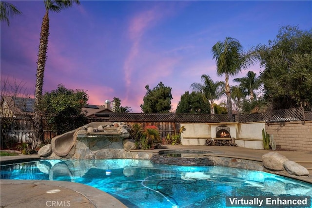 pool at dusk with an in ground hot tub