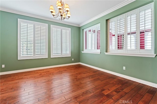 empty room featuring hardwood / wood-style flooring, ornamental molding, and an inviting chandelier