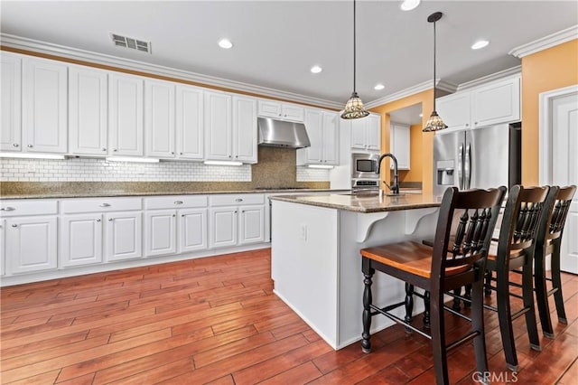 kitchen with white cabinetry, a center island with sink, dark stone counters, and decorative light fixtures