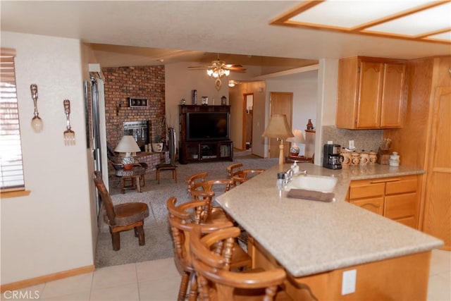 kitchen featuring ceiling fan, backsplash, kitchen peninsula, sink, and light tile patterned floors