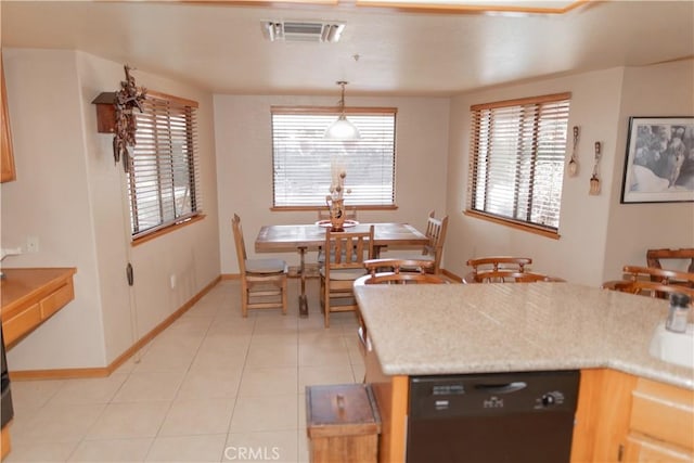 kitchen with decorative light fixtures, light tile patterned floors, light brown cabinets, and black dishwasher