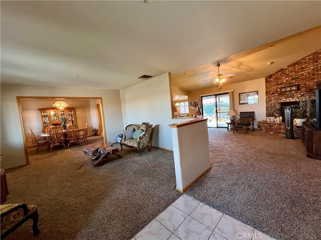 living room with vaulted ceiling, ceiling fan, light colored carpet, and a brick fireplace