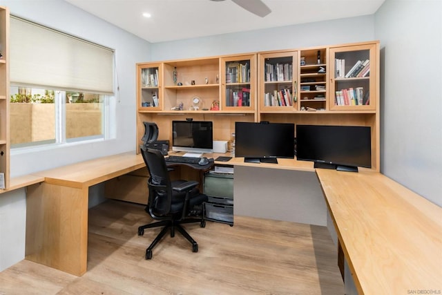 home office with ceiling fan, built in desk, and light wood-type flooring