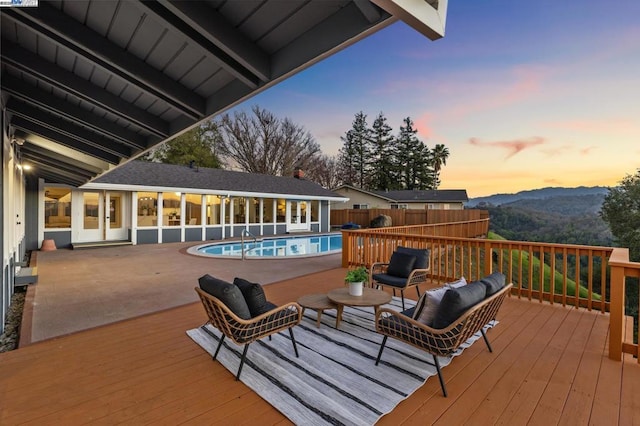 deck at dusk with a mountain view and a fenced in pool