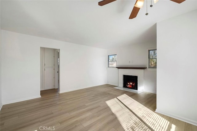 unfurnished living room with a brick fireplace, light hardwood / wood-style flooring, and ceiling fan