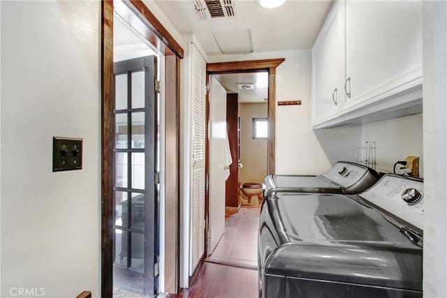 washroom with cabinet space, visible vents, washer and dryer, and wood finished floors