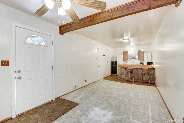 carpeted foyer entrance with ceiling fan, beam ceiling, and baseboards