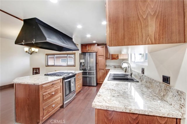 kitchen with sink, a kitchen island, stainless steel appliances, light stone countertops, and exhaust hood