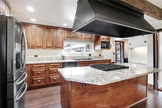 kitchen featuring stainless steel appliances, dark wood-type flooring, a sink, and wall chimney range hood