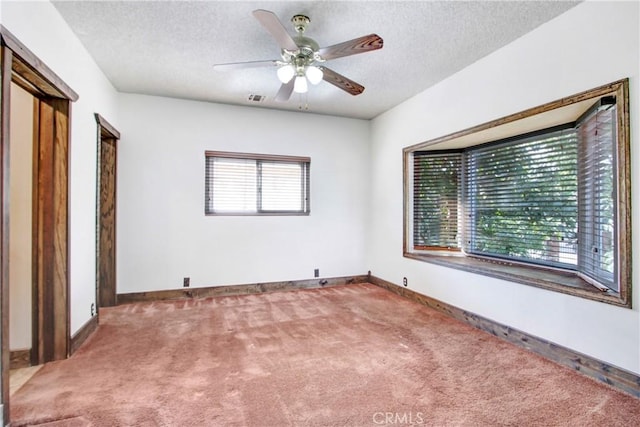 spare room featuring a textured ceiling, carpet, visible vents, and baseboards