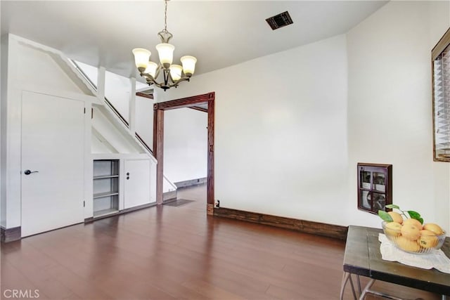 unfurnished dining area featuring a notable chandelier, visible vents, and wood finished floors