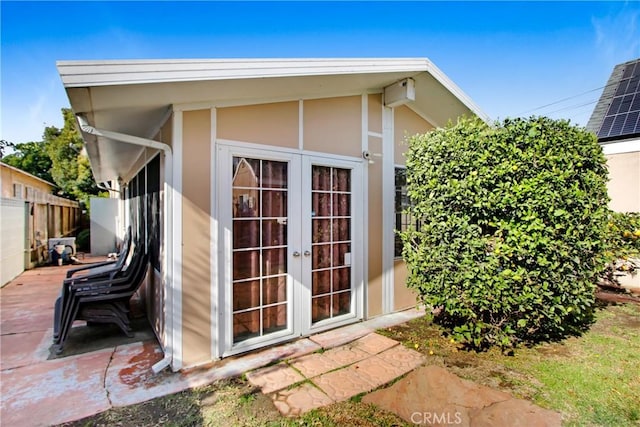 view of outbuilding featuring french doors and fence