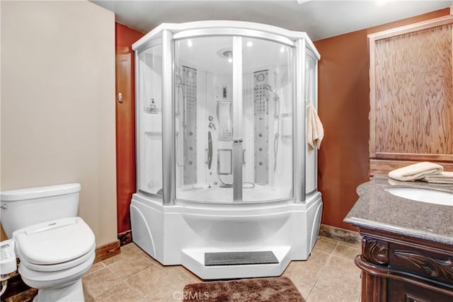 bathroom featuring vanity, a shower stall, toilet, and tile patterned floors