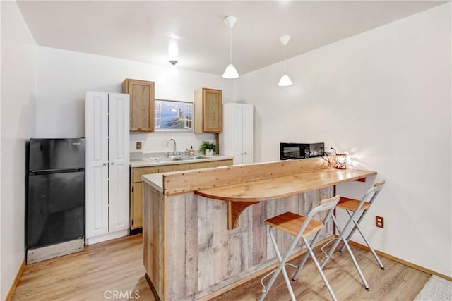 kitchen with light wood-style floors, light countertops, a sink, and black appliances