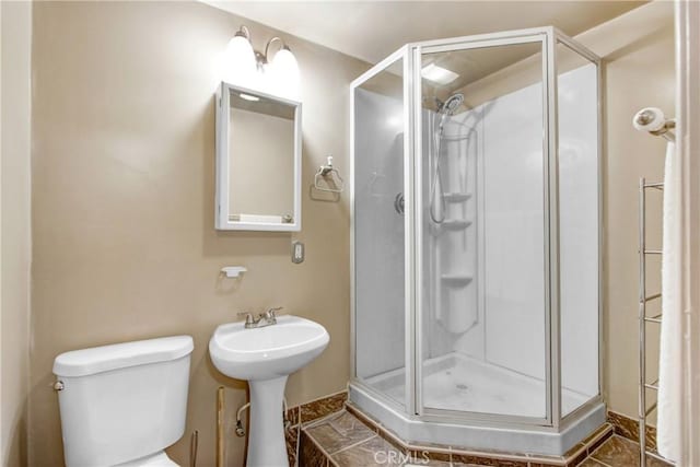 bathroom with a stall shower, a sink, and toilet