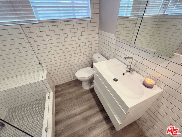 bathroom with toilet, vanity, tile walls, and hardwood / wood-style flooring