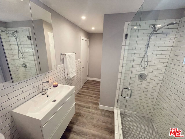 bathroom with wood-type flooring, backsplash, an enclosed shower, and vanity