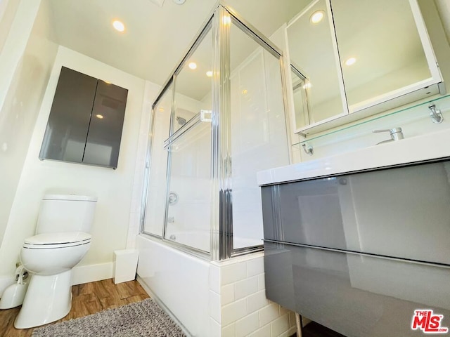 full bathroom featuring toilet, enclosed tub / shower combo, hardwood / wood-style flooring, and vanity