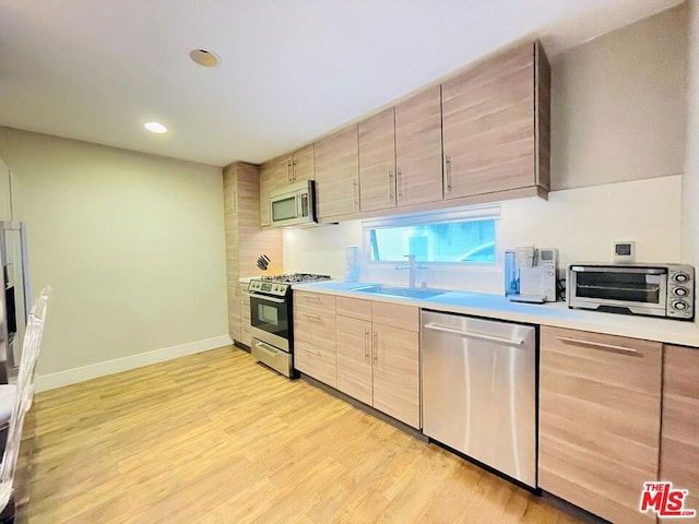 kitchen featuring sink, light brown cabinets, stainless steel appliances, and light hardwood / wood-style flooring